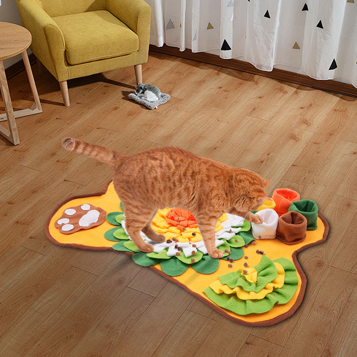 Chat roux qui fouille dans un tapis de fouille posé sur un plancher de bois